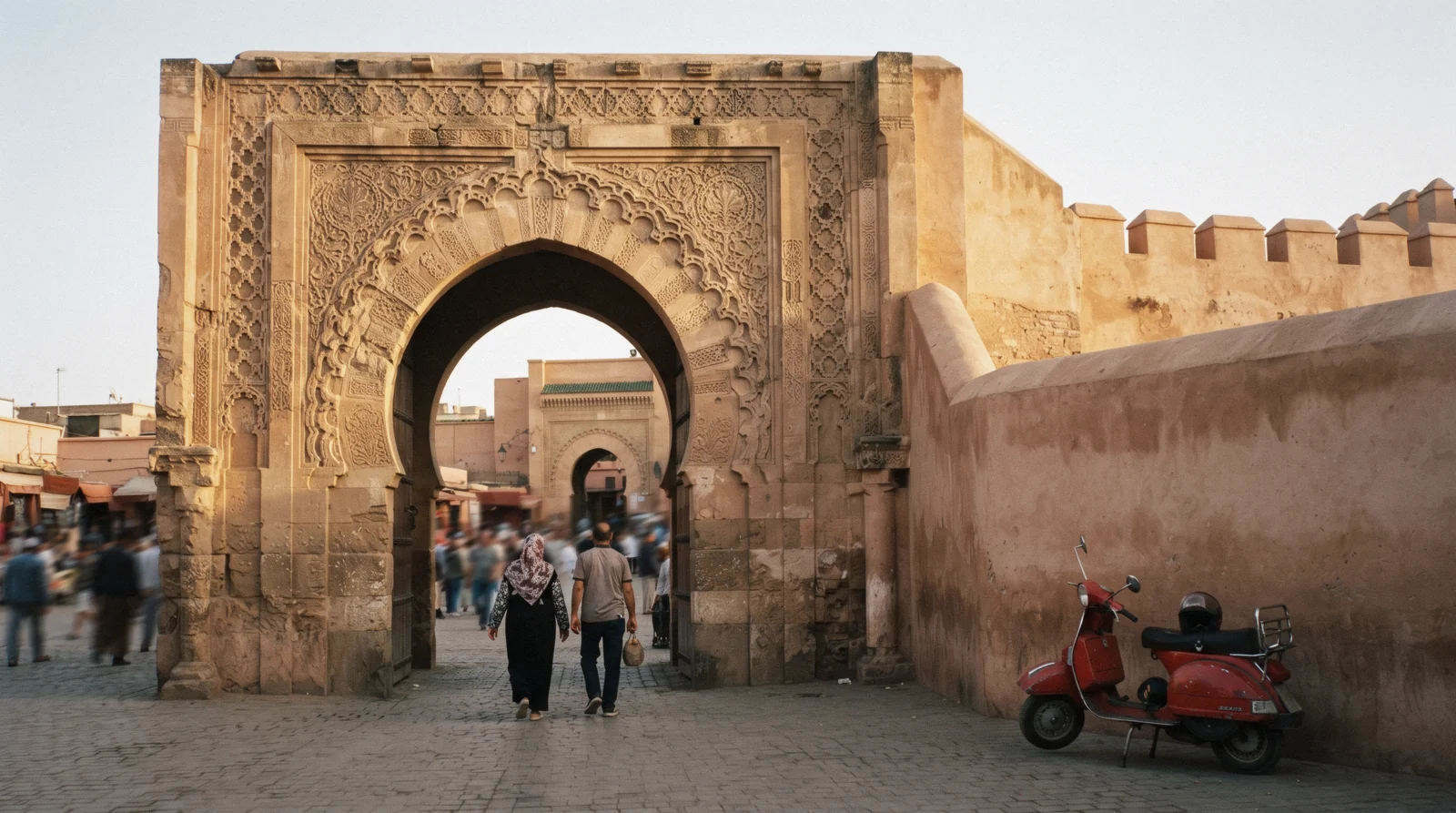 The carved sandstone horseshoe arch of Bab Agnaou warm in low sun with the rampart running east, Kasbah Marrakech