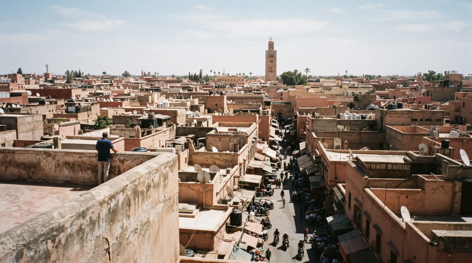 Hard vertical shadows falling across the medina lanes seen from a rooftop at midday, the hour that shapes one day in Marrakech